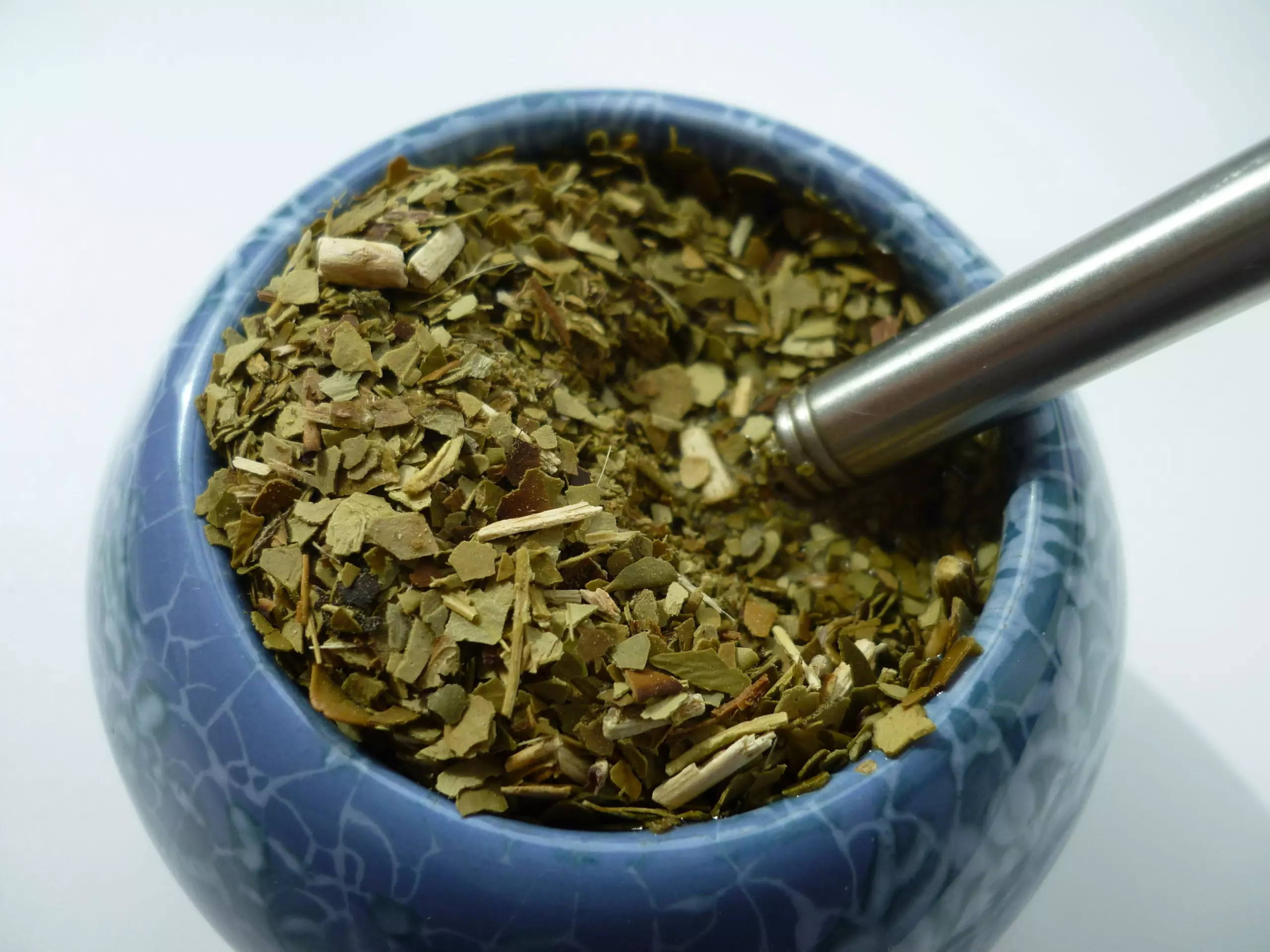 Verse yerba mate in een houten beker met bombilla.